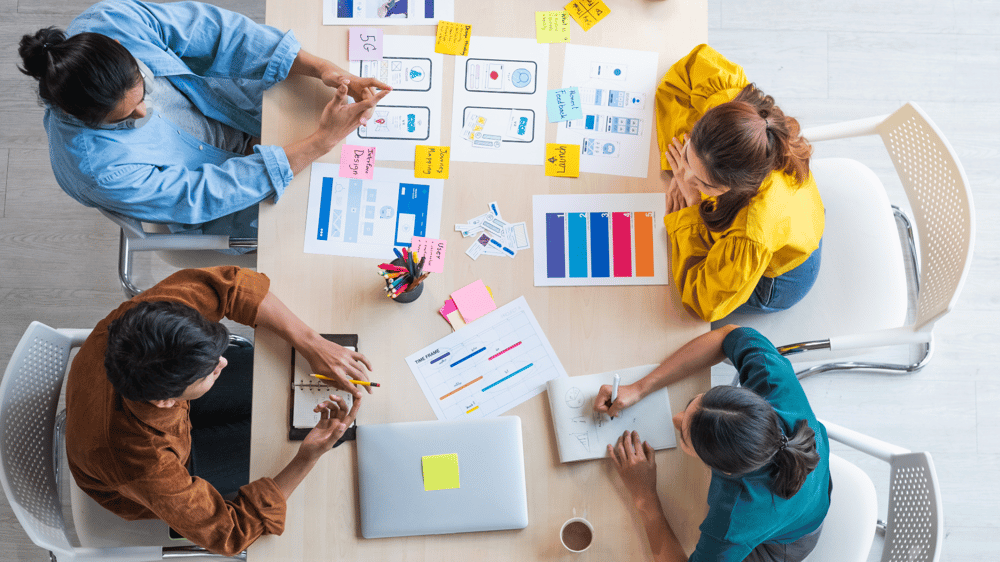 Top view ux developer and ui designer brainstorming about mobile app interface wireframe design on table with customer breif and color code at modern office. Creative digital development agency